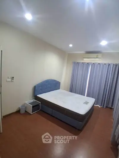Spacious bedroom with modern furnishings and natural light, featuring a comfortable bed and elegant curtains.