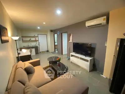 Modern living room with cozy sofa, flat-screen TV, and open kitchen layout in stylish apartment.