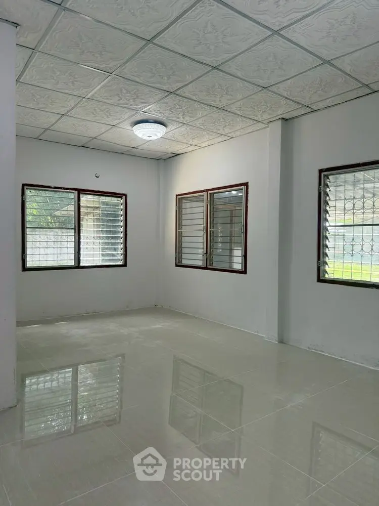 Spacious empty room with tiled floor and large windows, perfect for customization.