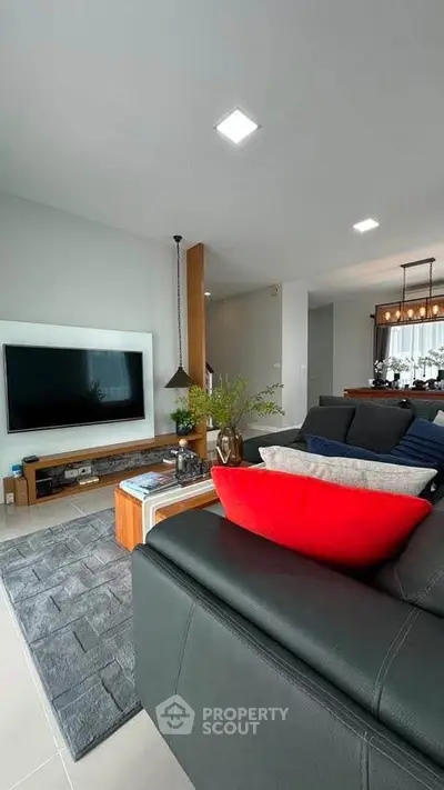 Modern living room with sleek black sofa, large TV, and stylish decor in a contemporary home.