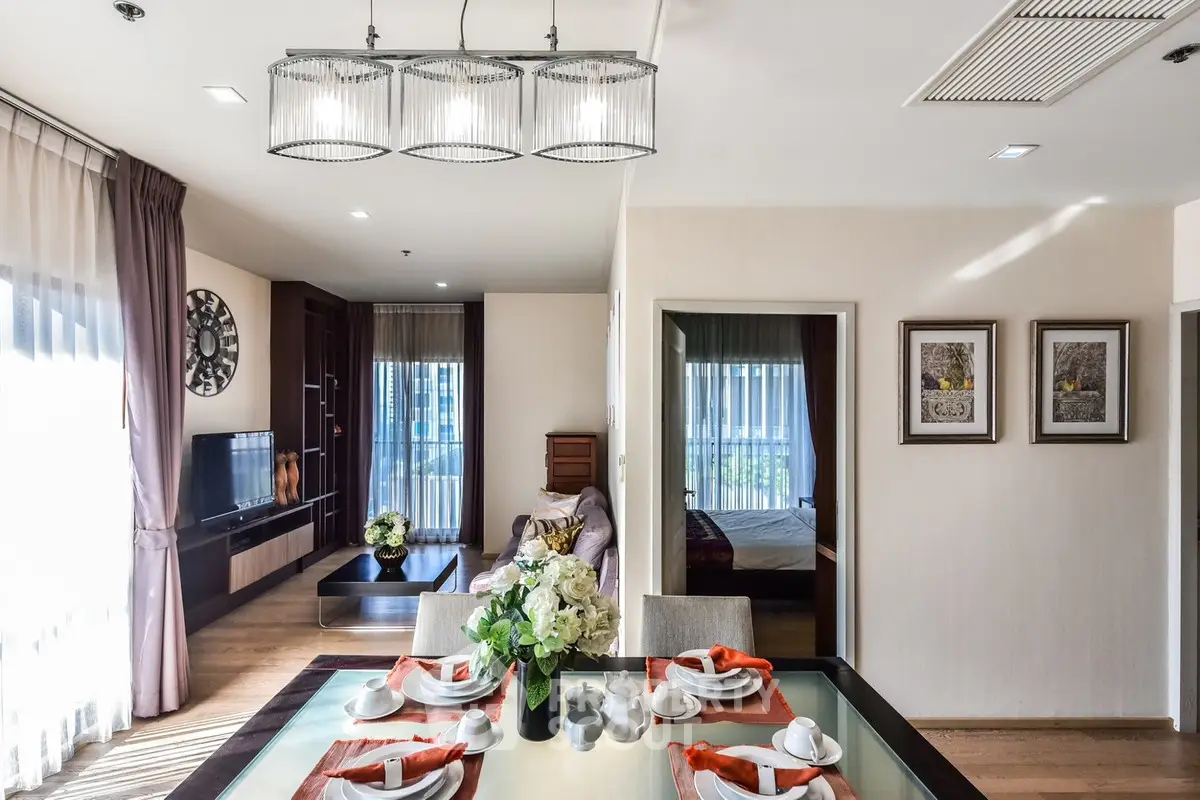 Elegant living room with dining area, modern decor, and natural light in a stylish apartment.