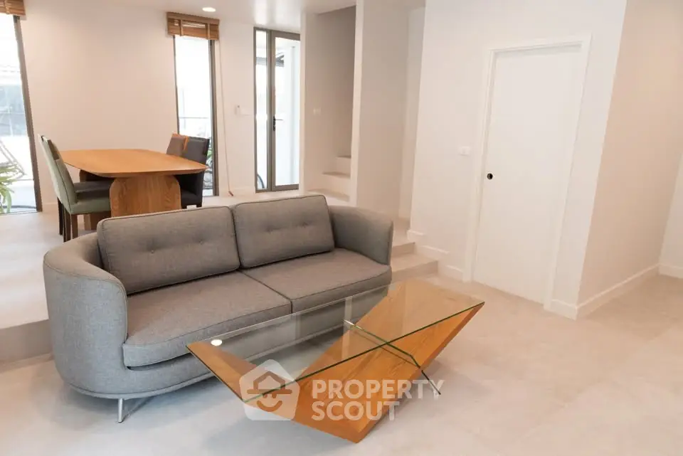 Modern living room with stylish sofa and glass coffee table in bright interior