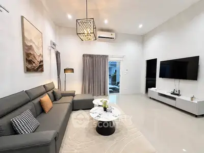 Spacious modern living room with elegant decor and large TV, perfect for relaxation and entertainment.