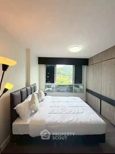 Spacious bedroom with large windows offering scenic views, modern furnishings, and ample natural light.