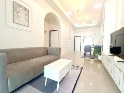 Elegant living room with modern decor and open layout, featuring a plush sofa and stylish lighting.