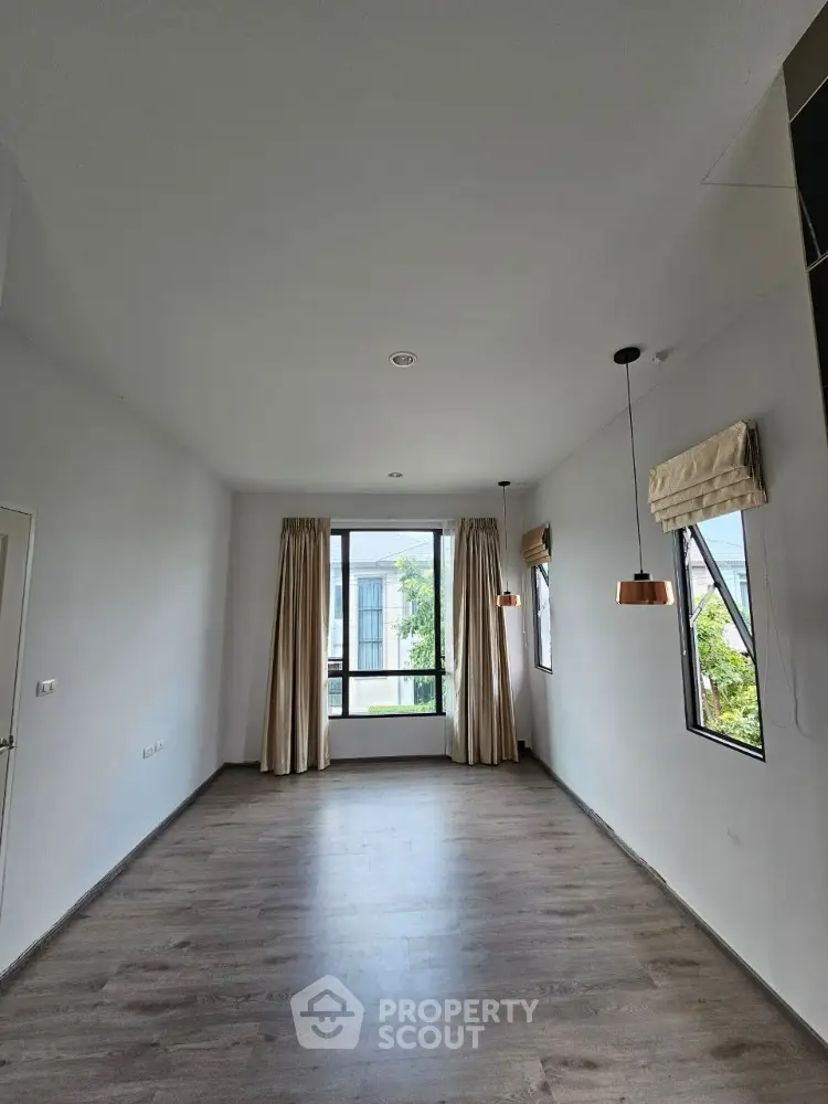 Spacious empty room with large windows and modern lighting, perfect for customization.