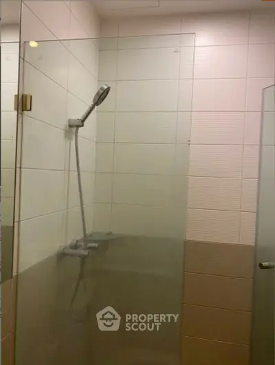 Modern bathroom with glass shower enclosure and sleek showerhead.