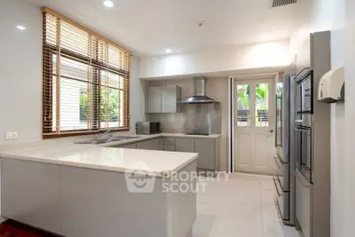 Spacious kitchen with modern appliances, ample countertop space, and sleek cabinetry, complemented by natural light filtering through the blinds.