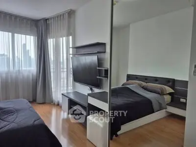 Modern bedroom with city view, featuring sleek furniture and large windows for natural light.