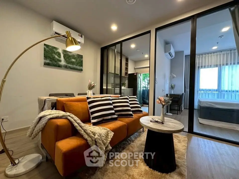 Modern living room with cozy orange sofa and stylish decor in open-plan apartment