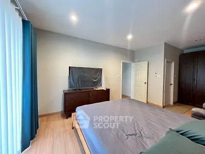 Spacious bedroom with modern decor and large TV, ideal for relaxation.