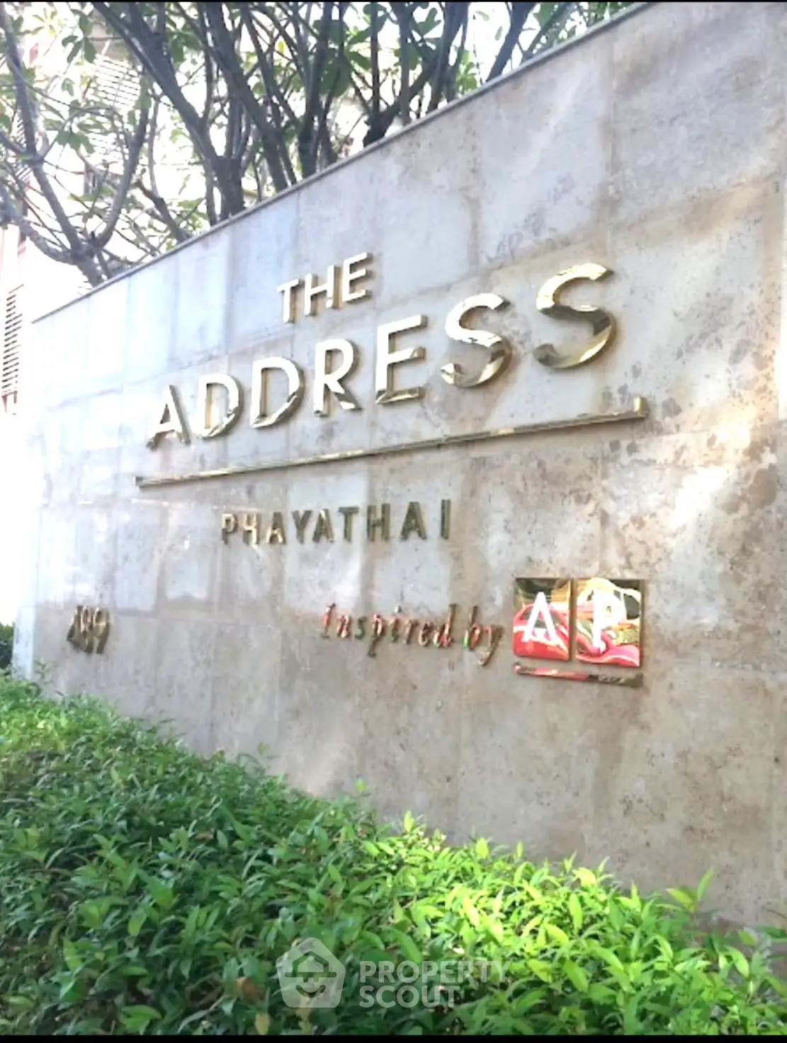 Elegant entrance sign of The Address Phayathai surrounded by lush greenery.