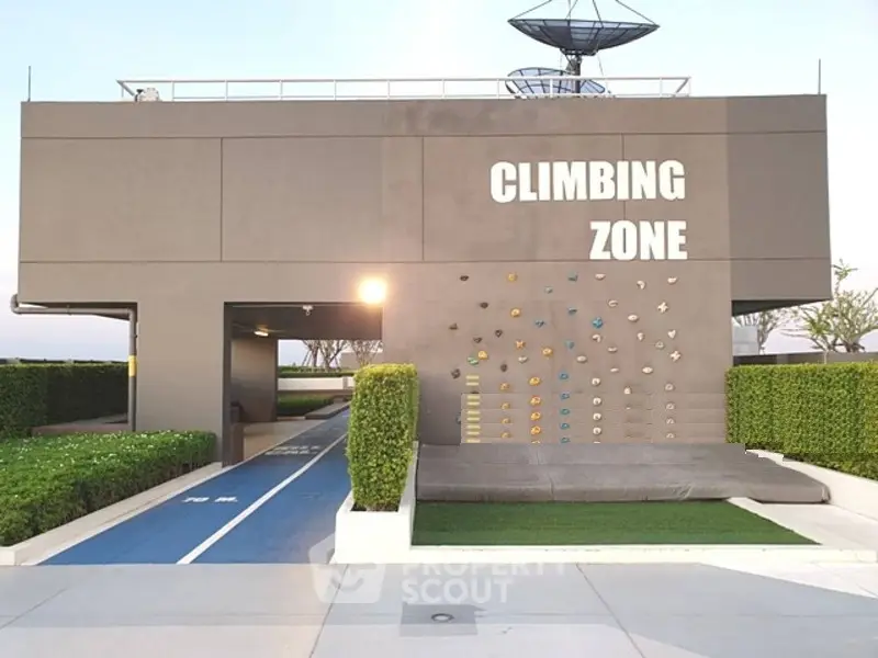 Modern building exterior with climbing wall and landscaped surroundings in a recreational area.
