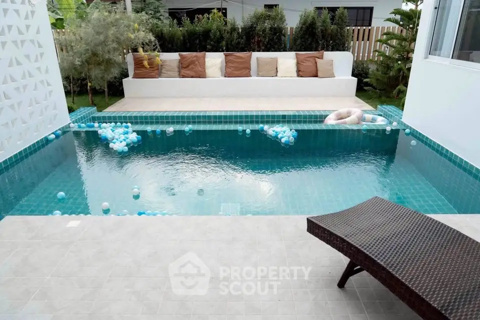 Charming backyard pool with modern seating and lush greenery, perfect for relaxation and entertainment.
