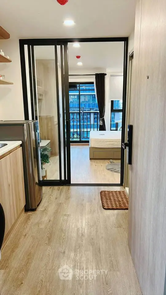 Modern studio apartment with open layout and balcony view, featuring sleek kitchen and cozy living space.