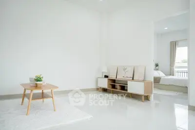 Bright minimalist living room with modern furniture and a glimpse of a cozy bedroom.
