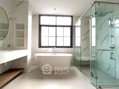 Luxurious modern bathroom with freestanding tub and glass shower enclosure.