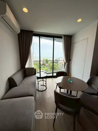 Modern living room with large windows offering a stunning city view, featuring sleek furniture and elegant decor.