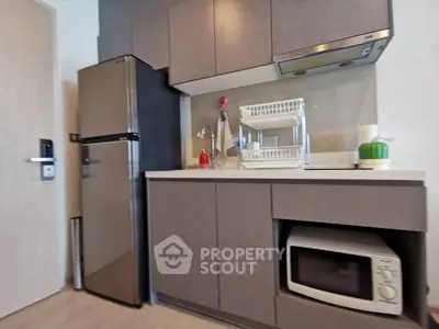 Modern kitchen with sleek cabinets, stainless steel fridge, and microwave oven