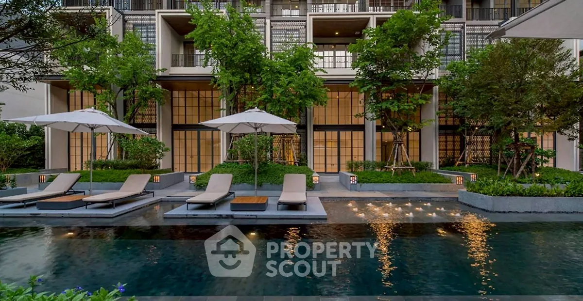 Luxurious modern apartment building with poolside lounge area and lush greenery.