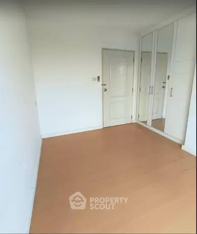 Spacious empty bedroom with mirrored wardrobe and wooden flooring