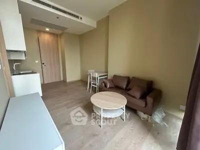 Modern living room with cozy brown sofa, round coffee table, and compact kitchen area in open layout.