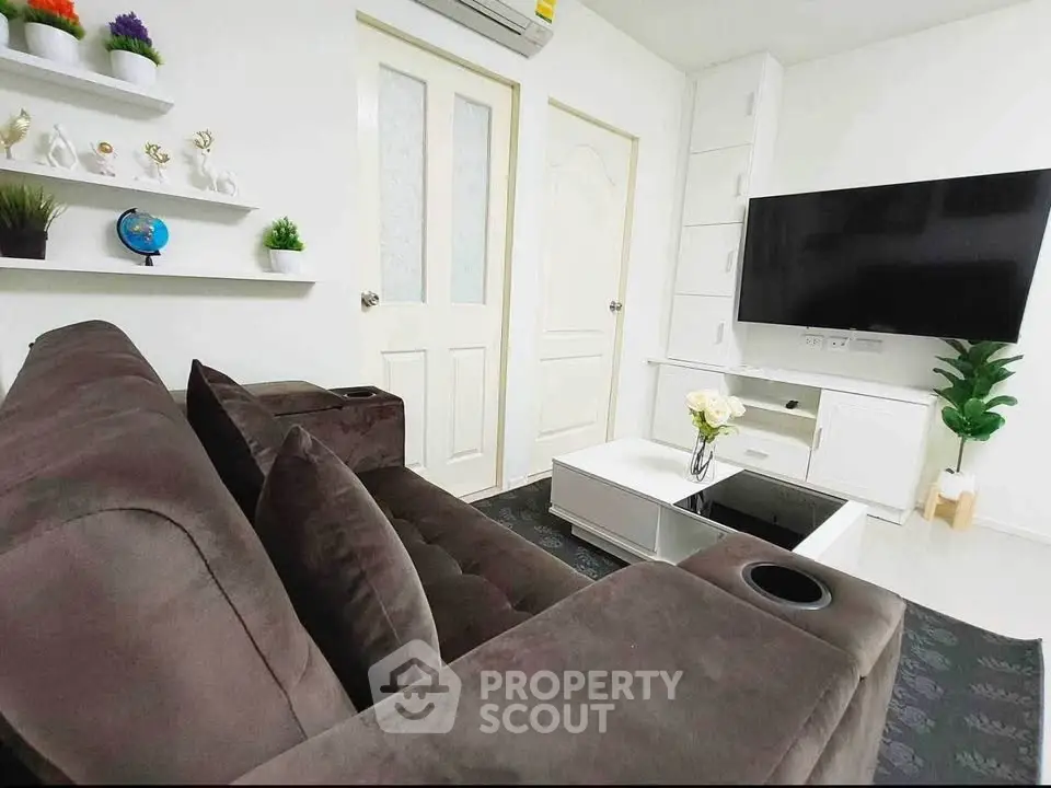Modern living room with plush brown sofa, wall-mounted TV, and stylish decor accents.