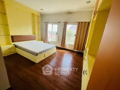Spacious bedroom with large windows and wooden flooring in a modern home.