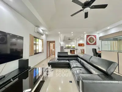 Spacious modern living room with sleek black leather sofa and open kitchen layout.