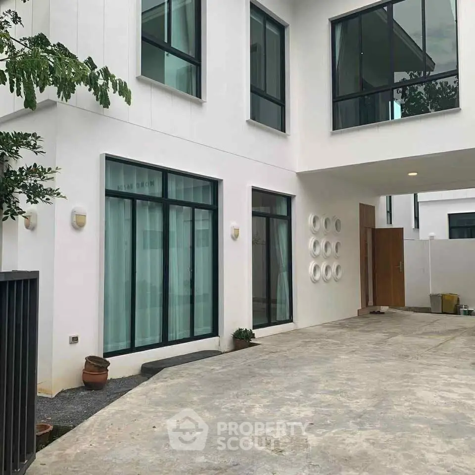 Modern white exterior of a contemporary home with large windows and driveway.