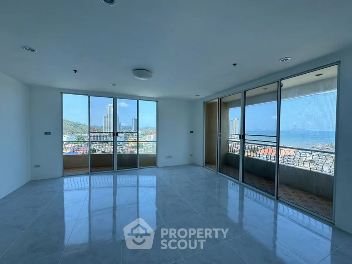 Spacious living room with large windows offering stunning city and sea views.