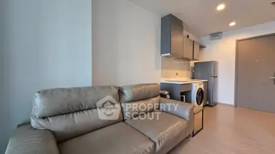 Modern apartment interior with sleek kitchen and cozy living area featuring a leather sofa.