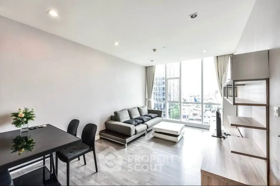 Modern living room with large windows and sleek furniture in a high-rise apartment.