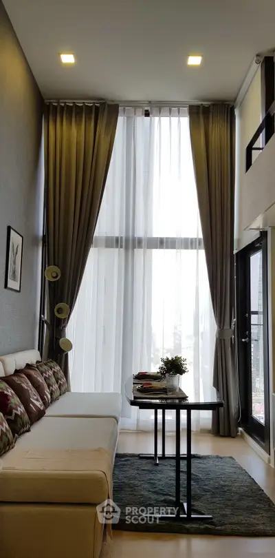 Modern living room with high ceilings and large windows, featuring elegant curtains and stylish decor.