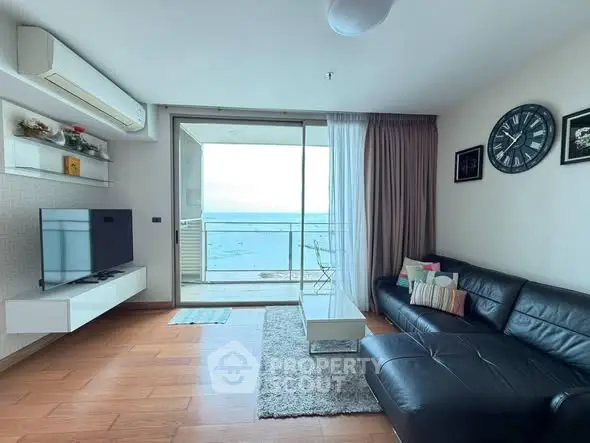 Spacious living room with ocean view and modern decor in beachfront apartment.