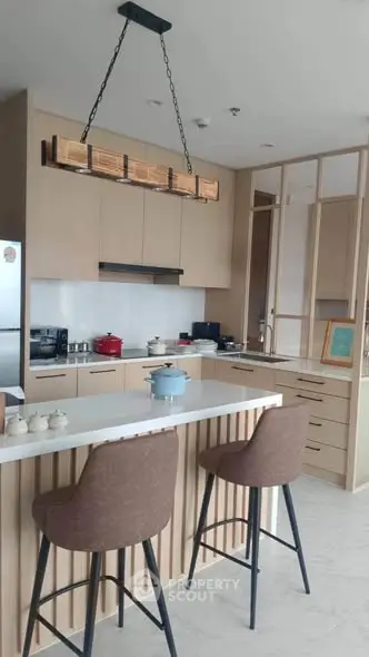 Modern kitchen with island, stylish lighting, and sleek cabinetry in a contemporary apartment.