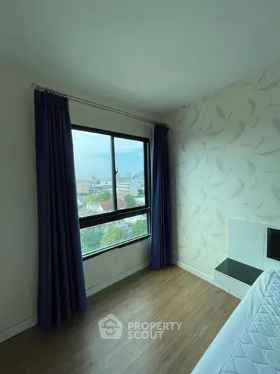Bright bedroom with large window offering stunning city view and elegant wallpaper.