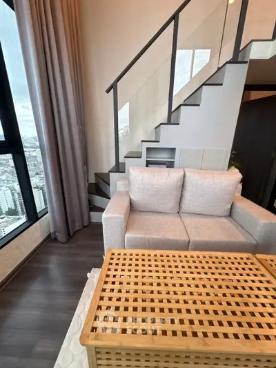 Modern living room with stylish staircase and city view, featuring cozy sofa and wooden coffee table.