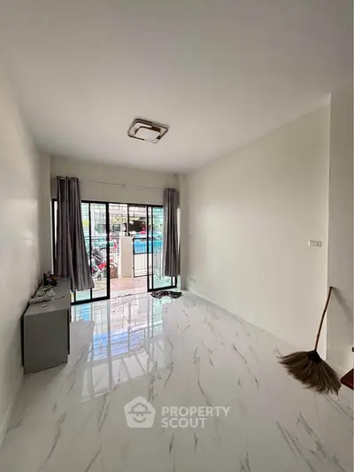 Spacious living room with glossy tiled floors and large windows leading to a balcony.