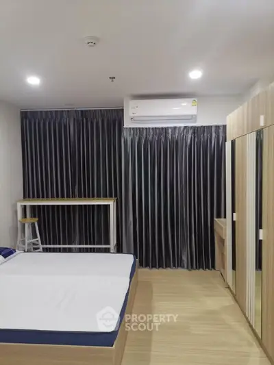 Modern bedroom with minimalist design featuring a bed, wardrobe, and air conditioning.
