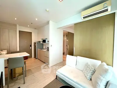 Modern open-layout living room with kitchen, featuring sleek furniture and bright lighting.