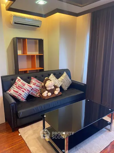 Cozy living room with modern black sofa, glass coffee table, and stylish decor