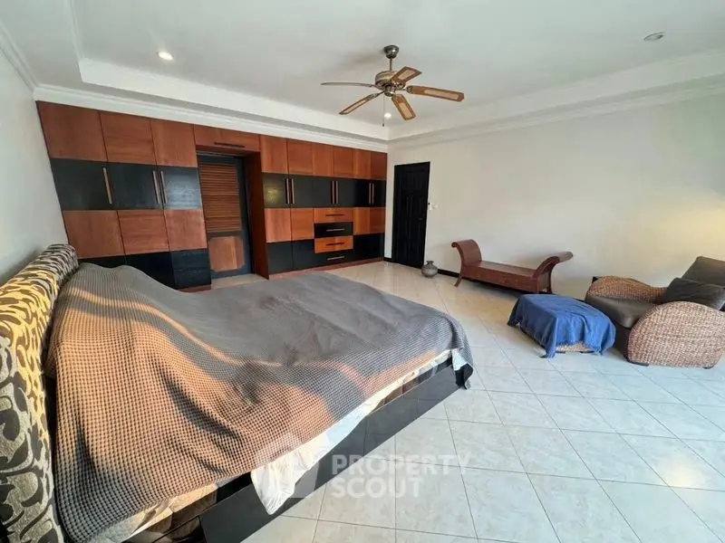 Spacious bedroom with elegant wooden furniture and ceiling fan