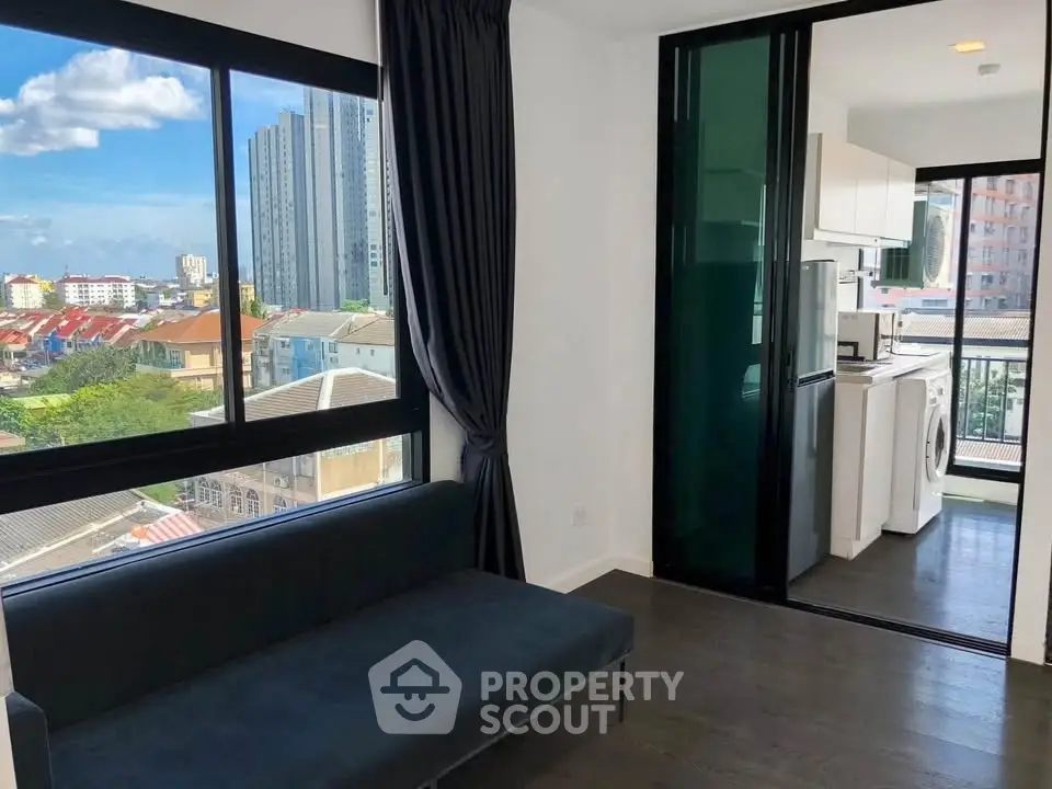 Modern apartment with large windows, city view, and sleek kitchen featuring washing machine.