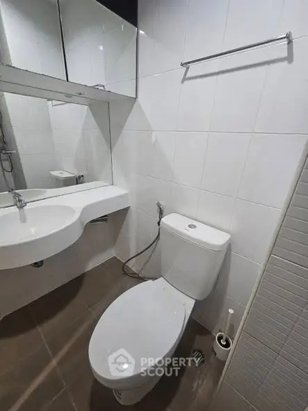 Modern bathroom with sleek white fixtures and large mirror, perfect for a contemporary home.