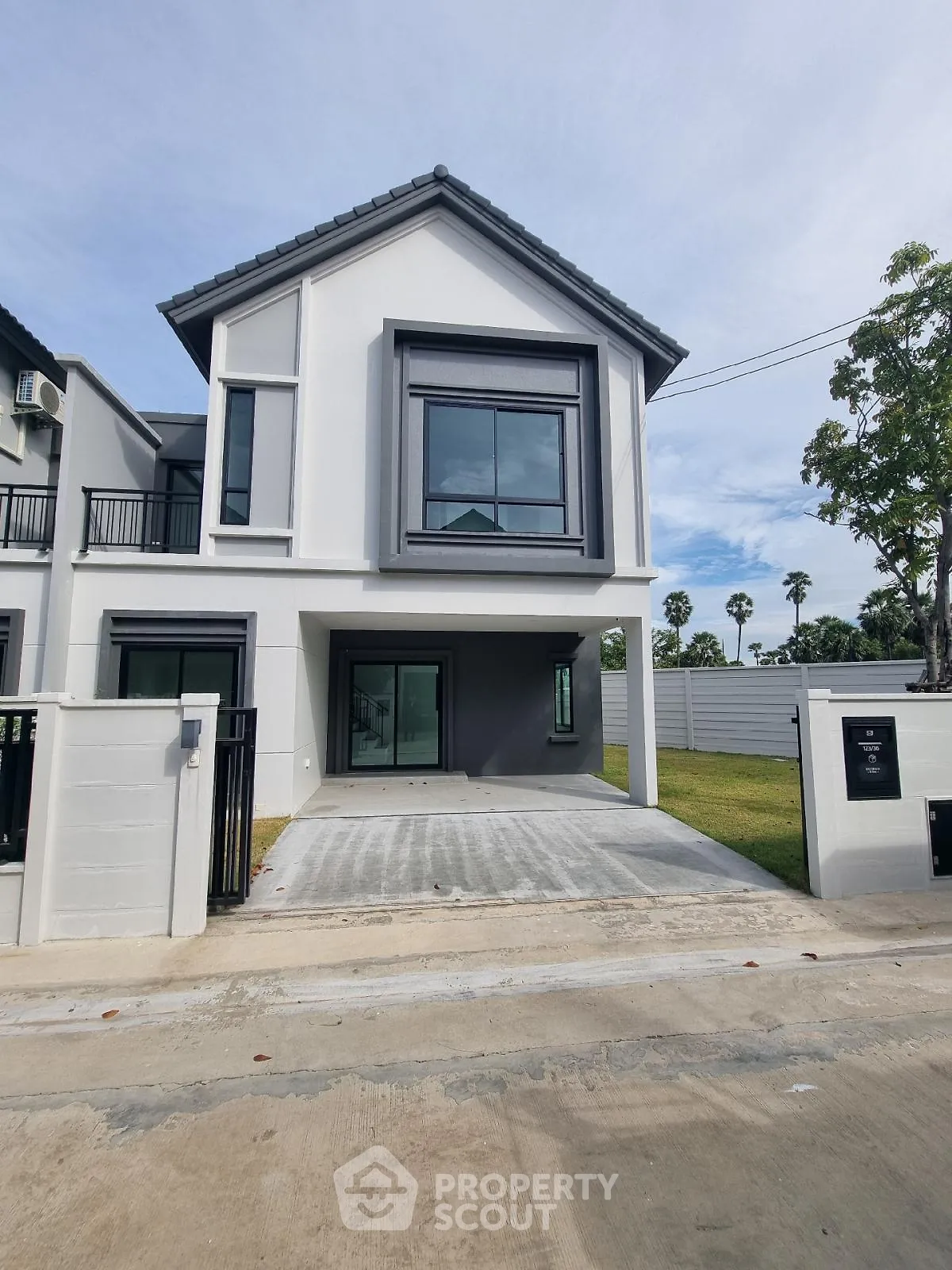 Modern two-story house with driveway and lush green surroundings