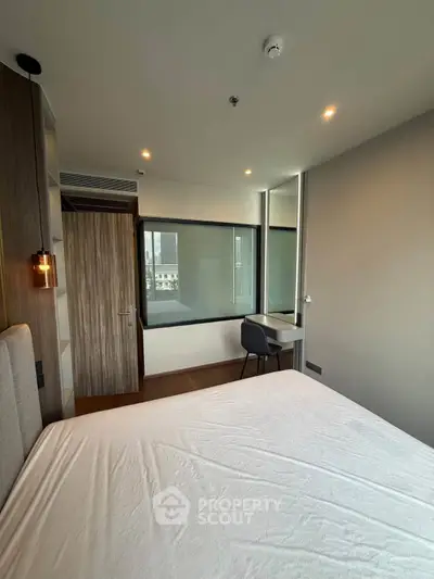 Modern bedroom with large window and stylish decor in a contemporary apartment.