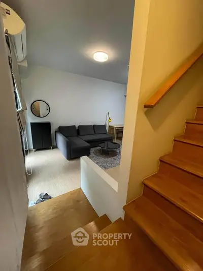Modern living room with cozy sofa and wooden staircase, perfect for relaxation and comfort.