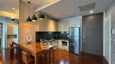 Modern kitchen with sleek cabinets, wooden dining table, and stainless steel appliances in a stylish apartment.
