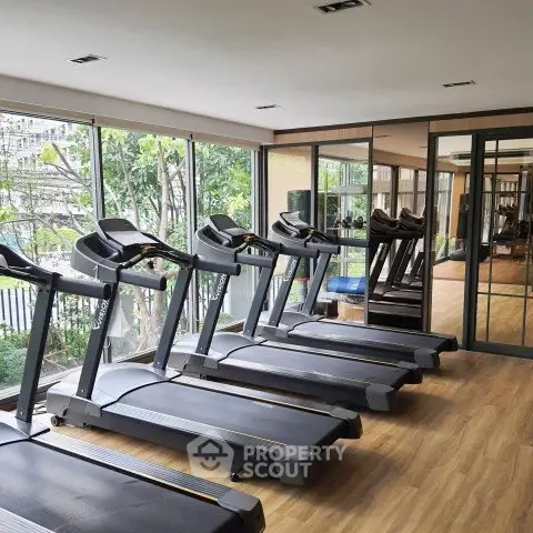Modern gym with multiple treadmills and large windows offering a scenic view.